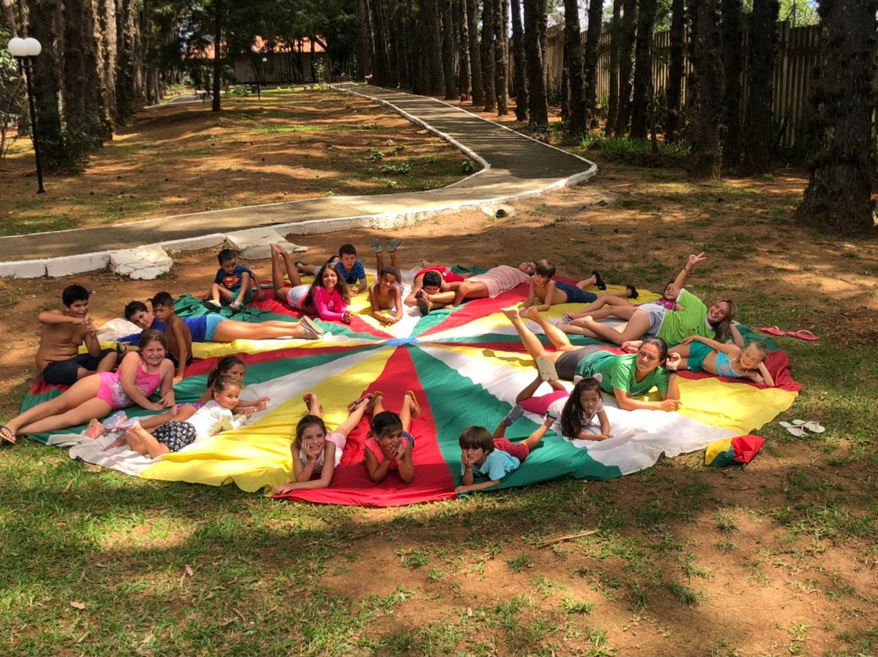 Crianças no paraquedas colorido durante a recreação