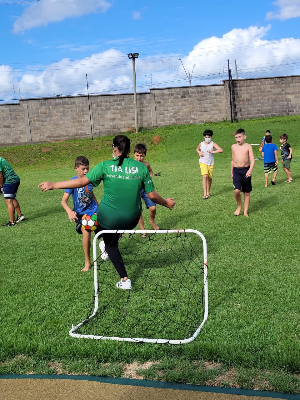 Crianças brincando futebol com monitora da Tia Lisi ao ar livre
