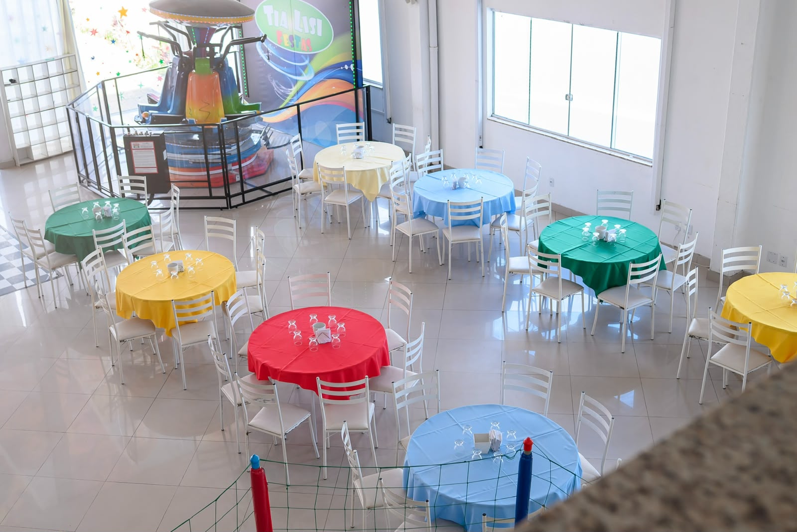Vista do salão com mesas coloridas e brinquedo carrossel