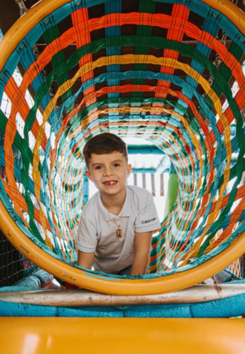Criança brincando no túnel colorido do playground